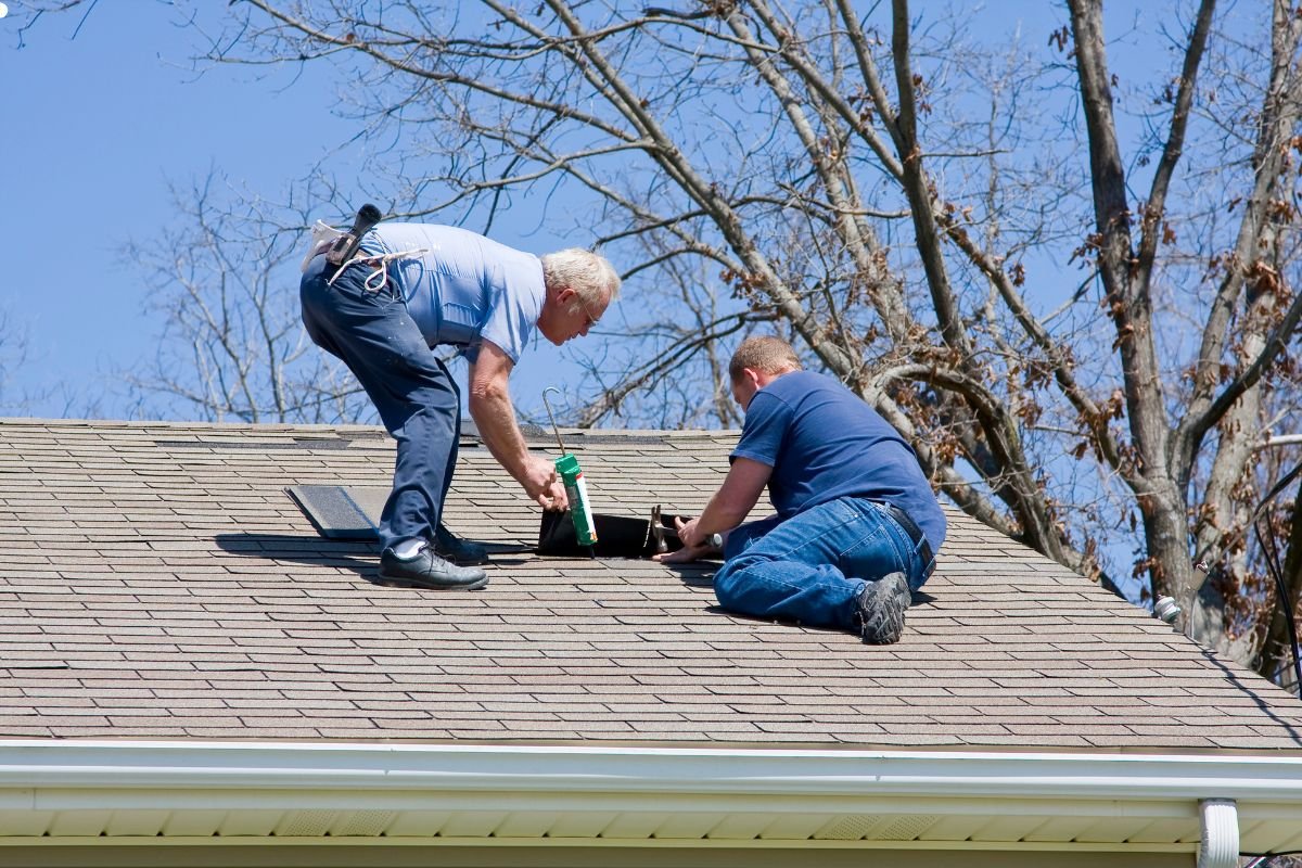 Two men repairing a damaged roof with a ladder, alongside an insurance policy document for reference.